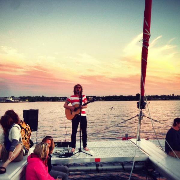 A musician playing at sunset on the Nauti-Cat