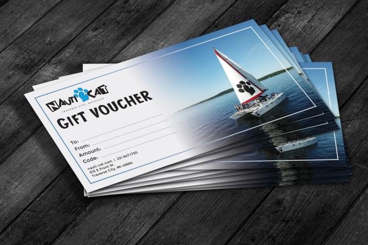 Stack of gift vouchers with sailboat image, labeled 'NautiCat' on wooden surface.